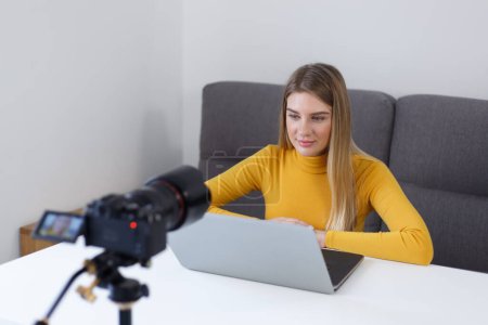 Photo for Beautiful young adult woman filming video blog content at home. Cheerful online teacher shoots educational material - Royalty Free Image