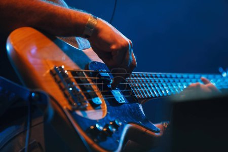 Photo for Bass guitar player performing on concert. Close up photo of professional guitarist playing solo part on stage - Royalty Free Image