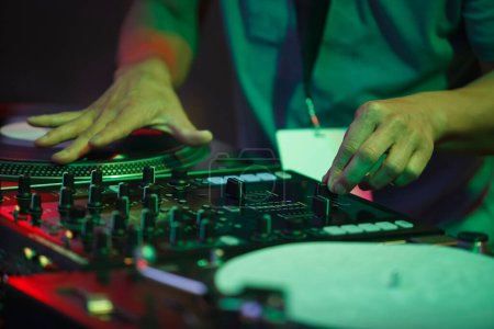 Téléchargez les photos : Hip hop dj scratches vinyl records on party in night club. Hands of professional disc jockey scratching record on turntable player - en image libre de droit