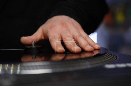 Photo for Hand of hip hop dj scrathing vinyl record on turntable. Professional disc jockey scratches records on stage - Royalty Free Image