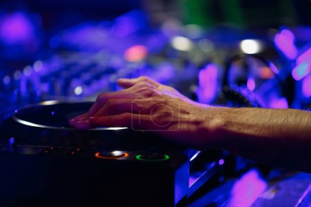 Photo for Club DJ plays music with professional cd turntable on party. Close up photo of disc jockey playing set on stage - Royalty Free Image