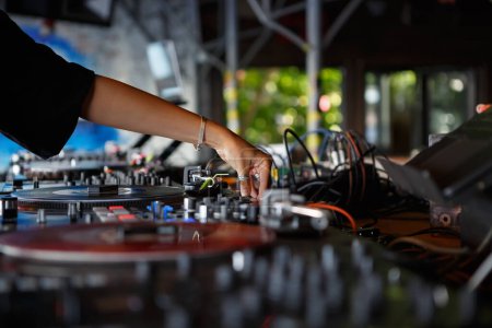 Téléchargez les photos : Femme DJ joue de la musique techno avec des platines vinyle sur la fête dans un bar. Mains de jeune femme mélangeant des disques sur scène - en image libre de droit