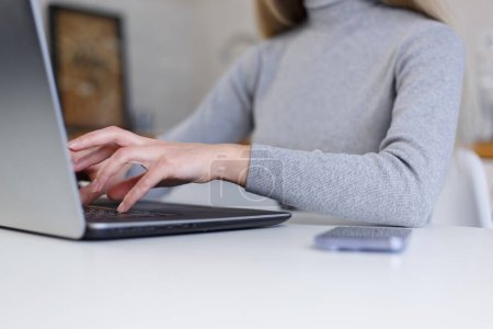 Téléchargez les photos : Jeune femme tapant le code sur l'ordinateur portable moderne à la maison. Programmeuse personne travaillant en ligne - en image libre de droit