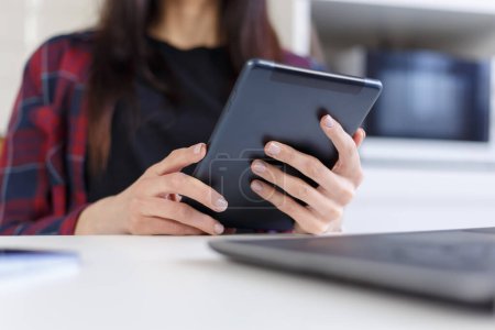 Foto de Young woman browsing internet on tablet computer. Close up photo of female person using modern portrable gadget - Imagen libre de derechos