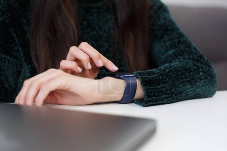 Foto de Female person browsing notifications on smart wrist watches in close up. Yong woman using modern smart watch gadget - Imagen libre de derechos