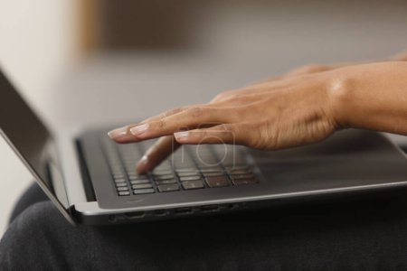Foto de Black female hands typing text on laptop keyboard. Unrecognizable BIPOC woman working on modern notebook pc in close up - Imagen libre de derechos