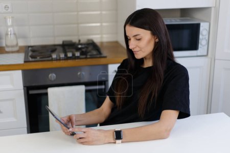 Photo for Beautiful white woman browsing internet on tablet computer at home. Young adult female person reading ebook on gadget - Royalty Free Image
