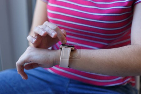 Foto de Young woman using smart watch. White girl browsing notifications on modern smart wrist watches in close up - Imagen libre de derechos