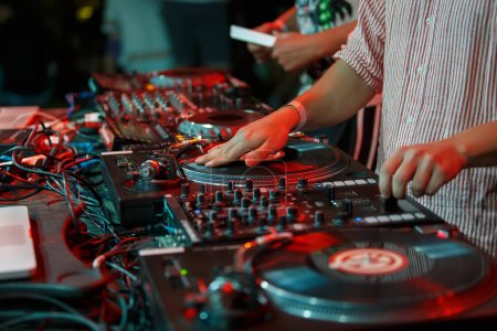 Photo for Hip hop dj scratches vinyl record on party in night club. Hands of professional disc jockey scratching records on turntable - Royalty Free Image