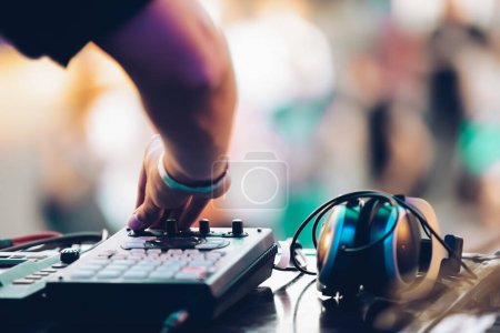 DJ plays music on summer festival. Disc jockey using midi controller device on concert