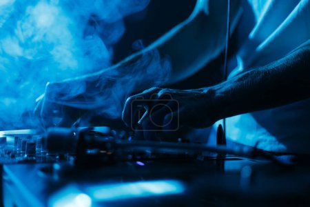 Téléchargez les photos : Techno party DJ mixant des disques vinyles dans une boîte de nuit sombre. Photo rapprochée de disc jockey jouant de la musique sur scène - en image libre de droit