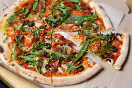 Photo for Italian pizza with arugula, tomato sauce, mushrooms and black olives delivered in cardboard box for lunch - Royalty Free Image