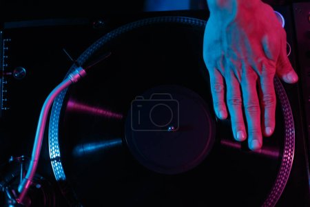 Téléchargez les photos : Overhead photo of hip hop disc jockey scratching vinyl record on turntable player in night club - en image libre de droit