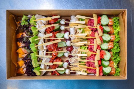 Photo for Big box with snacks on sticks delivered for food catering service on venue. Delicious natural appetizers for wine party. Shot in flat lay style directly from above - Royalty Free Image