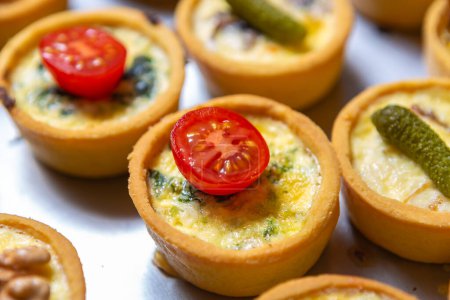 Foto de Delicious canape with cheese and cherry tomatoes baked in restaurant kitchen. Wine party appetizer dish in close up - Imagen libre de derechos