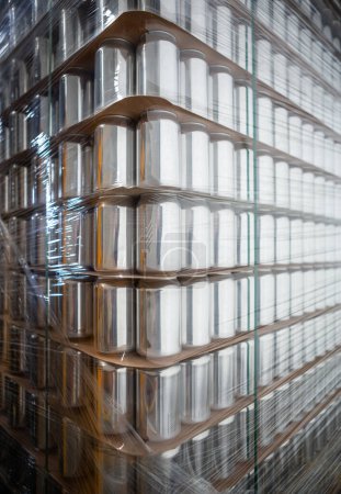 Foto de Stock de latas de aluminio nuevas en el almacén de la cervecería. Primer plano de la foto de la plataforma con nuevos envases de metal para bebidas frías - Imagen libre de derechos
