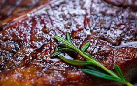 Téléchargez les photos : Bifteck juteux au t-bone cuit sur le gril et servi avec de l'herbe de romarin au restaurant. Délicieuse viande de bœuf rouge préparée avec une recette traditionnelle - en image libre de droit