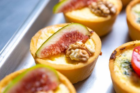 Téléchargez les photos : Delicious canape with fresh figs, walnut and melted cheese. Groupd of gourmet snacks for wine party being prepared in restautant kitchen - en image libre de droit