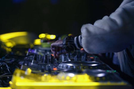 Foto de Hip hop dj girl toca música en el escenario. Manos de disc jockey femenino mezclando pistas musicales en fiesta en club nocturno. - Imagen libre de derechos