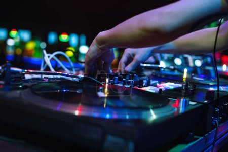 Foto de Hip hop DJ mezclando música con discos de vinilo y mezclador de sonido. Manos de disc jockey jugando en la fiesta en el club nocturno. - Imagen libre de derechos