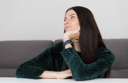 Photo for Young adult brunette woman thinking about future with a smile. Portrait of beautiful white female person sitting at home in thought - Royalty Free Image