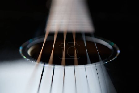Téléchargez les photos : Beautiful black acoustic guitar in close up. Soung hole and metal strings in focus. - en image libre de droit