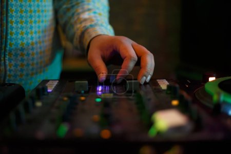 Téléchargez les photos : Hip hop dj plays music with sound mixer. Hand of disc jockey on cross fader knob. Professional disk jokey mixing musical tracks on party in night club - en image libre de droit