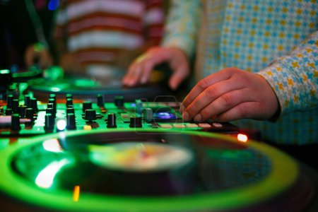 Foto de Hip hop dj scratches vinyl record on turn table. Professional disc jockey scratching records with turntable and sound mixer devices - Imagen libre de derechos