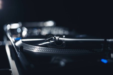 Photo for DJ turntable plays vinyl record with music on party in nightclub. Professional disk jokey audio equipment in close up - Royalty Free Image