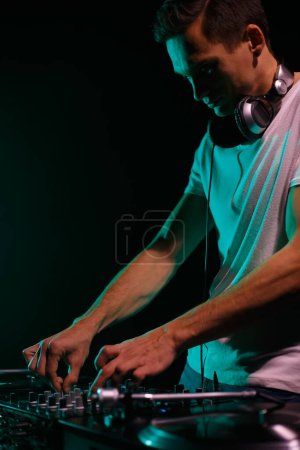 Foto de Club DJ plays music with sound mixer and vinyl turntables. Disc jockey mixing hip hop tracks on party in night club - Imagen libre de derechos