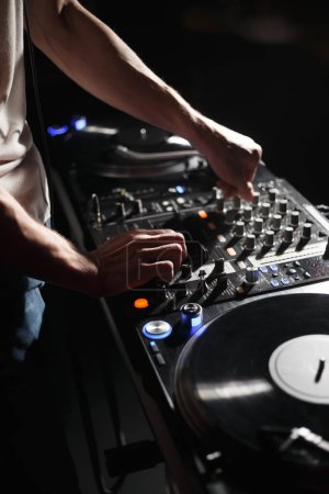 Téléchargez les photos : Techno DJ joue au set avec tourne-disque en vinyle et mixeur sonore dans le night club. Disque jockey professionnel mixant des disques sur des platines - en image libre de droit