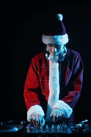 Téléchargez les photos : Santa DJ joue de la musique de Noël sur l'événement de célébration. Disc jockey mixant des morceaux musicaux le soir du Nouvel An - en image libre de droit