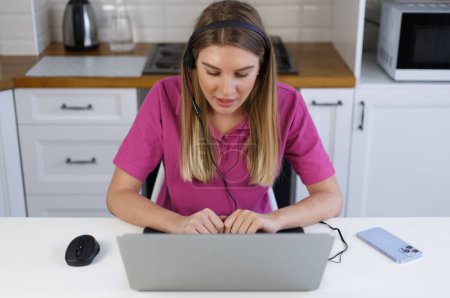 Téléchargez les photos : Young woman in headset working as online support assistant. White female person talking on video call - en image libre de droit