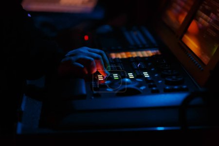Photo for Stage lighting technician working on concert. Professional lights engineer using lights controller desk on music festival - Royalty Free Image
