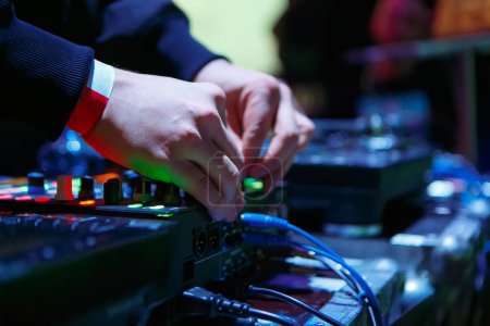Photo for Club DJ adjusting sound mixer on stage. Professional disc jockey playing music with sound mixing controller - Royalty Free Image