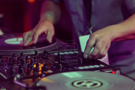 Téléchargez les photos : Hip hop DJ scratches vinyl records on turntables. Hands of disc jockey scratching record on turn table player in close up - en image libre de droit