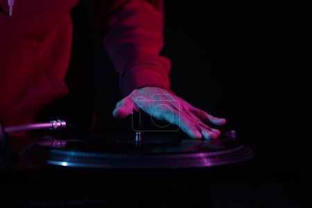 Téléchargez les photos : Hip hop disc jockey scratches vinyl disc on turn table. Club dj scratching records on turntables in nightclub - en image libre de droit