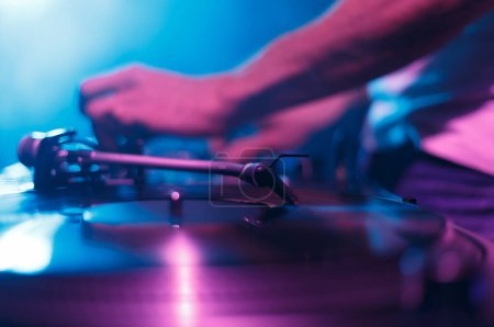 Photo for Club DJ paying music with vinyl records and turn table. Disc jockey mixing musical tracks on party in nightclub, focus on turntables needle - Royalty Free Image