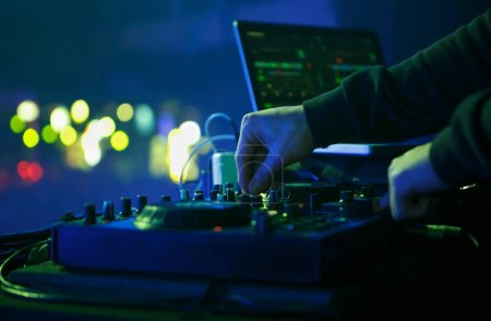 Téléchargez les photos : DJ playing electronic music set on party in night club. Close up photo of disc jockey mixing musical tracks with midi controller device - en image libre de droit