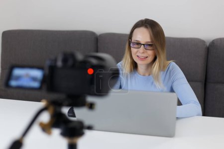 Photo for Teacher filming educational video course at home. Portrait of friendly white woman speaking on camcorder while filming a blog - Royalty Free Image