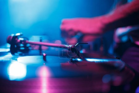 Téléchargez les photos : Turntable plays vinyl record with hip hop music on party in night club. Analog dj turn table player on concert stage. - en image libre de droit