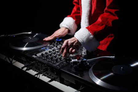 Foto de Disc jockey for Christmas party. DJ wearing traditional red Santa Claus costume plays music on vinyl turntables - Imagen libre de derechos