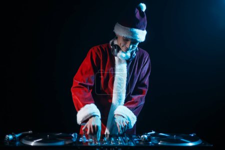 Foto de Santa DJ tocando música en la fiesta de Navidad en el club nocturno. Disco jokey en rojo tradicional juego de juegos de disfraces de Navidad - Imagen libre de derechos