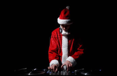 Téléchargez les photos : Santa Claus DJ mixant de la musique pour Noël. Jeune disc jockey portant traditionnel costume de Noël rouge joue ensemble - en image libre de droit