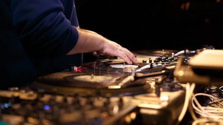 Foto de Hip hop dj rayando discos de vinilo en tocadiscos en la fiesta en el club nocturno. El disc jockey profesional rasca el disco analógico con música - Imagen libre de derechos