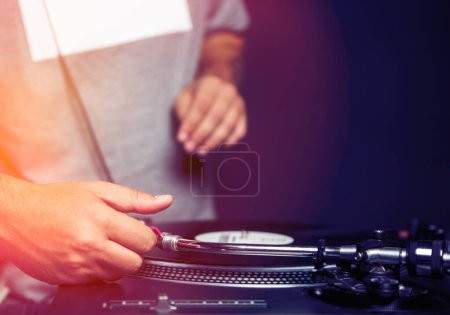 Photo for Hands of professional hip hop dj plays music.Disc jockey put turntables needle on black vinyl record with music on concert in night club.Party djs audio equipment in close up.Musician playing set - Royalty Free Image
