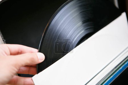 Téléchargez les photos : Dj contenant un disque vinyle avec de la musique pour tourne-disque. Écoutez les morceaux de musique en haute qualité fi avec des disques analogiques et des platines - en image libre de droit