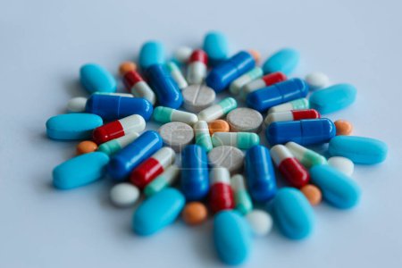 Foto de Pile of colorful medical pills on blue background. Different chemical drugs produced to cure disease - Imagen libre de derechos