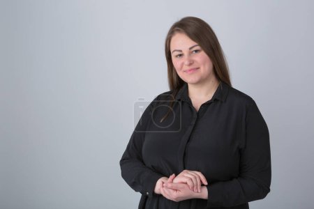 Foto de Cheerful plus size woman in casual black shirt posing in the studio. Portrait of friendly white overweight female - Imagen libre de derechos