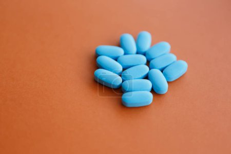 Foto de Montón de pastillas médicas azules sobre fondo naranja. Suplementos farmacéuticos para el tratamiento de enfermedades - Imagen libre de derechos